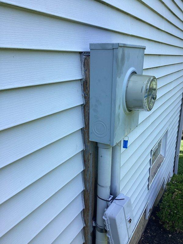 Responded to service call for electrical panel mounting concern. Upon inspection, found electrical meter housing and panel mounted to backing board that was separating from exterior wall, allowing water infiltration behind assembly. Documented existing conditions with photographs showing meter socket, PVC conduit installation, and deteriorated wooden backing support. Exterior assessment completed and findings reported to property contact for repair authorization.