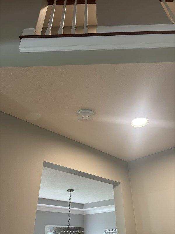 Converted hardwired smoke detectors to battery-powered units in residential property. Installed new battery-operated smoke alarms on ceiling locations in main living area and upper level near staircase, ensuring proper placement and functionality. All units tested and confirmed operational with illuminated status indicators.