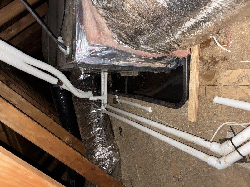 Responded to emergency service call for 2-year-old attic-mounted mini split system with active water leak. Upon arrival, unit was shut off by customer due to excessive water discharge. Inspected attic installation and identified condensate drain line blockage causing water overflow from drain pan. Cleared obstruction from primary drain line, verified proper pitch and routing of PVC condensate piping, and tested system operation. Confirmed proper drainage flow, checked refrigerant levels, and verified unit returned to normal operation without further leakage.