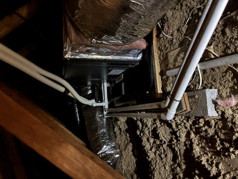 Responded to emergency service call for 2-year-old attic-mounted mini split system with active water leak. Upon arrival, unit was shut off by customer due to excessive water discharge. Inspected attic installation and identified condensate drain line blockage causing water overflow from drain pan. Cleared obstruction from primary drain line, verified proper pitch and routing of PVC condensate piping, and tested system operation. Confirmed proper drainage flow, checked refrigerant levels, and verified unit returned to normal operation without further leakage.