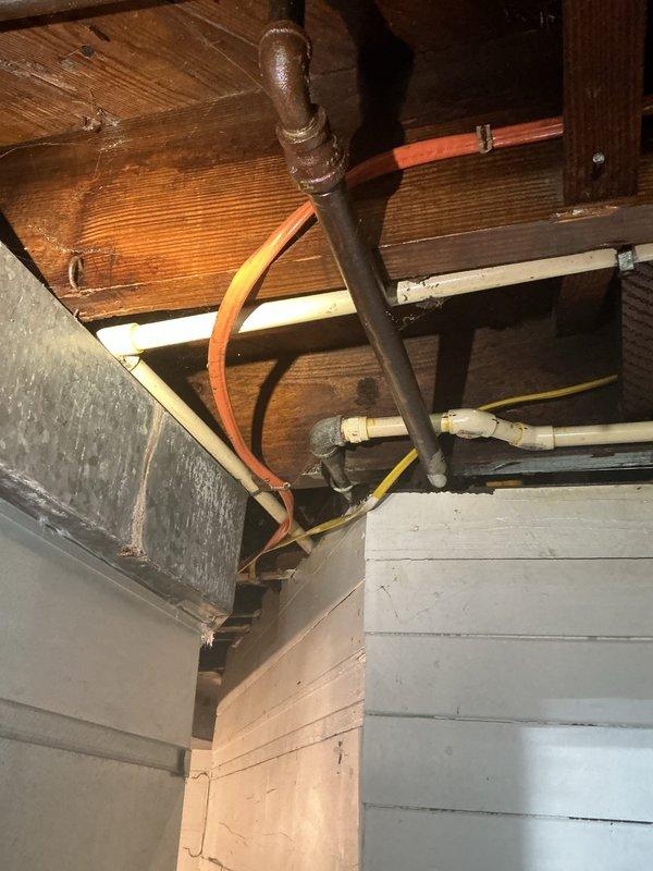 Replaced deteriorated galvanized piping with new copper piping in crawl space and basement utility area. Removed heavily corroded shutoff valves and fittings exhibiting significant oxidation and rust damage at floor-wall junction, installed new copper pipe runs and brass fittings to restore proper water supply functionality and prevent future leaks from corroded connections.