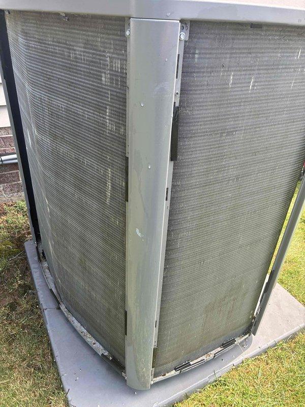 Performed routine maintenance inspection on residential air conditioning system. Examined indoor evaporator coil and filter assembly, noting diamond-patterned mesh filter in proper working condition with drainage line secured. Inspected outdoor condenser unit on concrete pad, observing weathered heat exchanger coils with accumulated environmental debris typical of outdoor exposure. System operational at time of service.