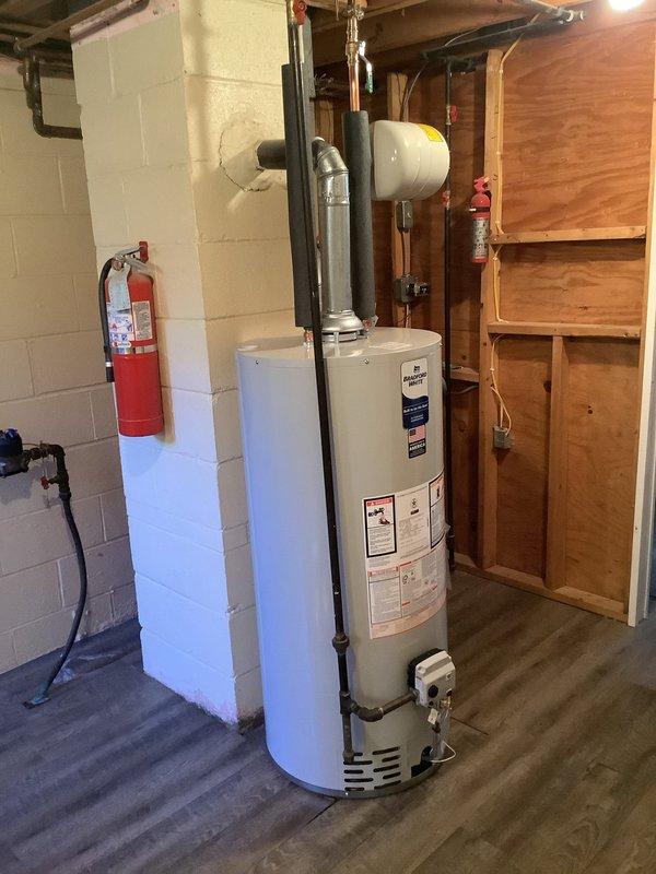 Replaced existing 40-gallon water heater with new Bradford White 40-gallon short model in basement utility area. Installed new water shut-off valve and gas shut-off valve on supply lines. Connected copper water lines with brass fittings and installed expansion tank to system. Verified all connections for proper operation and leak-free performance. Unit includes 6-year tank warranty and was installed with metallic flue pipe venting system.