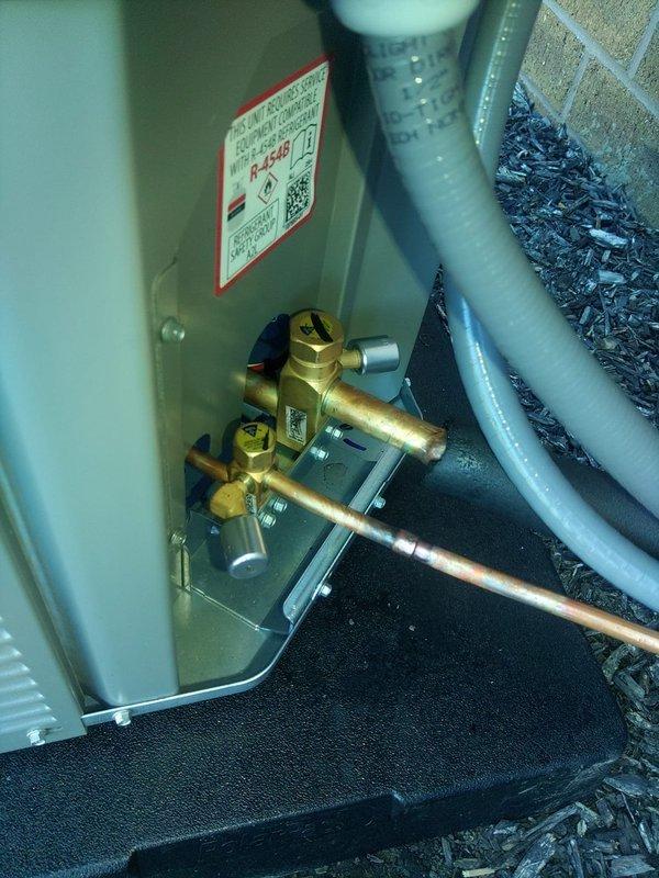 Completed installation of outdoor A/C unit and evaporator coil system utilizing R454B refrigerant. Installed brass manifold valve assembly with copper line connections, mounted unit on vibration-dampening pad against exterior brick wall, and verified system pressures and temperatures within manufacturer specifications using digital manifold gauges.