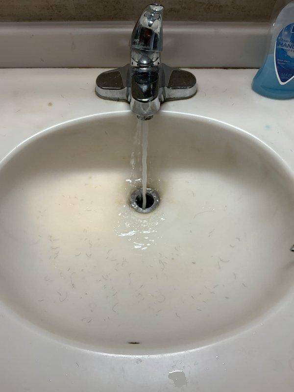 Responded to service call for clogged bathroom sink. Upon arrival, assessed the drainage issue and inspected the P-trap assembly beneath the vanity. Removed and cleaned the blue PVC trap, clearing accumulated debris causing the blockage. Verified proper water flow through the drain system and confirmed all connections were secure with no leaks present. Tested faucet operation and drainage performance to ensure complete restoration of normal function.