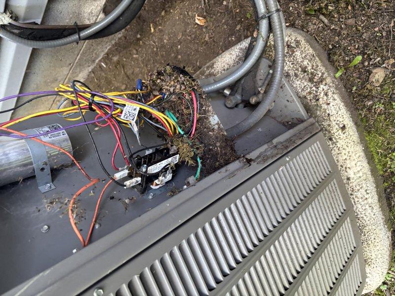 Responded to service call for 8-year-old air conditioning unit serving front zone of residence. Upon arrival, performed system inspection and discovered extensive organic debris accumulation within outdoor condensing unit, including dried grass, plant matter, and nesting materials that had infiltrated the electrical compartment and surrounding internal components. Removed top access panel to assess contamination level and found debris interfering with electrical connections and wire bundles. Thoroughly cleaned and removed all organic material from unit interior, including areas around contactor, wiring harness, and control components. Inspected all electrical connections and wire nuts for damage or deterioration caused by debris accumulation. Verified proper operation of contactor and electrical components after cleaning. Reinstalled access panel and confirmed unit operation. System restored to normal function with clear airflow pathways and unobstructed electrical components.