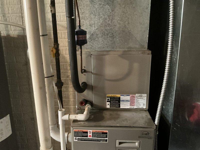 Completed HVAC system replacement for no cooling condition. Installed new gray furnace unit with evaporator coil in basement utility area against cinderblock wall, with proper PVC condensate drainage, gas lines, and metallic flexible ductwork connections. Installed new outdoor condenser unit on concrete pad in backyard with copper refrigerant lines and electrical conduit properly routed to exterior wall, system operational upon completion.