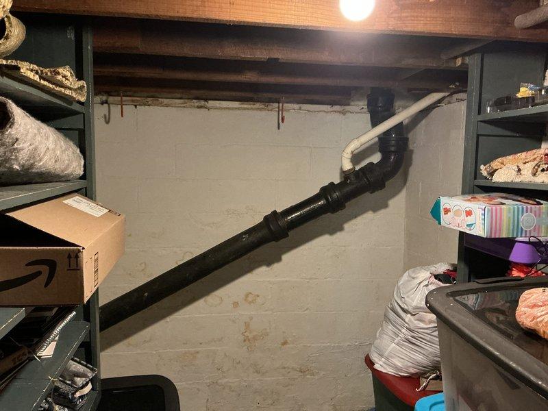 Responded to main line drainage issue where flushing the upstairs toilet caused air bubbles and splashing in the downstairs toilet. Upon inspection, identified significant rust staining on basement plumbing assembly indicating long-term deterioration of metal piping sections. Assessed drainage system configuration including PVC and aging metal pipe connections, gray PVC trap junction, and corrugated drainage lines. Documented existing plumbing conditions showing water-related deterioration at pipe connections and recommended monitoring for potential backflow issues given the cross-fixture symptoms indicating partial main line obstruction.