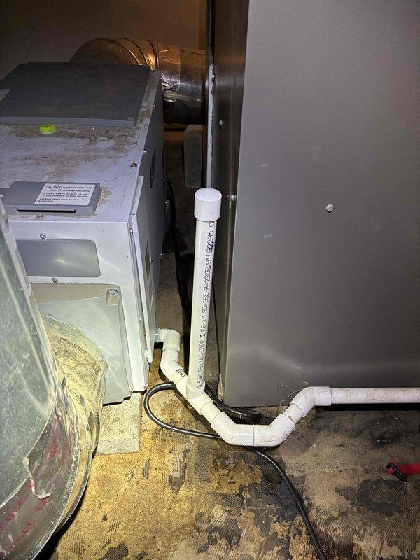 Responded to report of water leak from 3-year-old Aprilaire humidifier system. Upon inspection, identified active leak originating from humidifier assembly connected to furnace unit. Examined condensate drain lines, PVC piping connections, and humidifier water supply components. Documented equipment condition including heat exchanger assembly, refrigerant lines, and drainage system configuration. Assessed humidifier mounting, water panel condition, and drain connections for proper operation and potential failure points causing water discharge onto mechanical room floor.