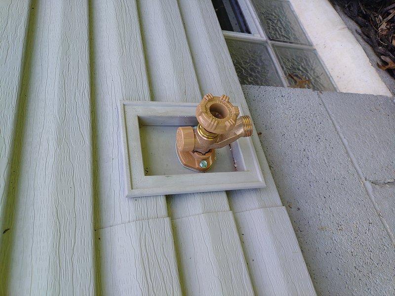 Installed two frost-free hose bibs with ball valves on the exterior of the residence. The front spigot was mounted on light-colored vinyl siding within a white recessed mounting box, while the rear spigot was installed on gray composite siding with a matching recessed access panel. Both brass fixtures were securely fastened to the exterior walls and properly sealed to prevent water intrusion, replacing the previous outdoor water connections with freeze-resistant units.