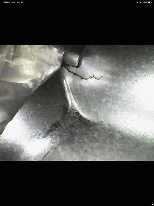 Responded to service call for non-functional air conditioning system in basement area with excessive heat buildup. Upon inspection, found 15+ year old unit with significant maintenance issues including severely clogged evaporator coil with heavy dust and debris accumulation restricting airflow, and visible crack in metal ductwork compromising system integrity. Documented equipment condition with photos showing extent of deterioration and lack of previous maintenance on aging system.