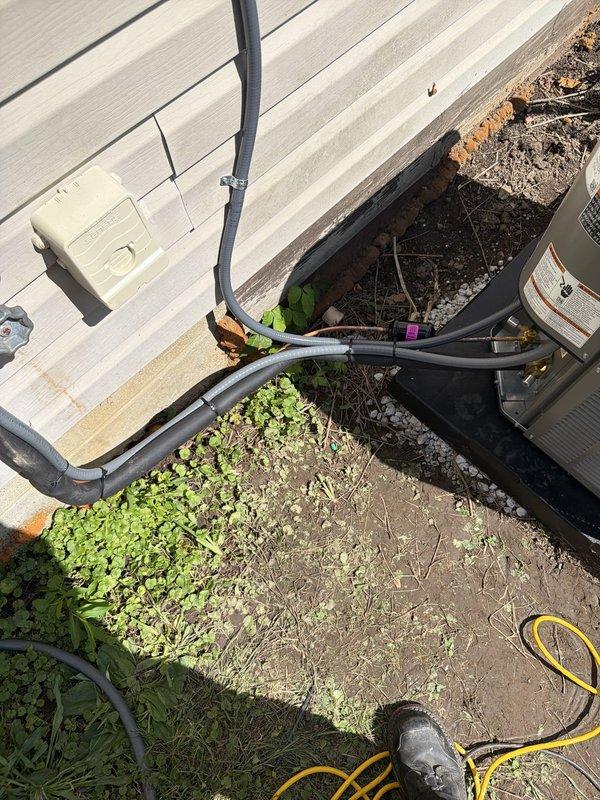 Completed installation of 80% efficiency furnace and air conditioning system at residential property. New outdoor condensing unit was positioned on pad against exterior wall with proper clearance, refrigerant lines were run and insulated along siding to interior connection point, and electrical disconnect box was mounted per code requirements. System was tested and confirmed operational upon completion.