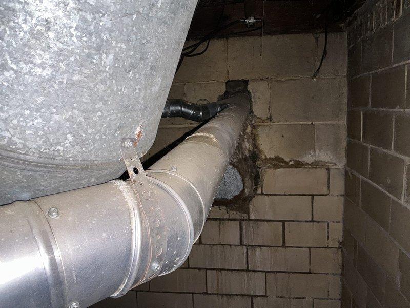 Conducted on-site assessment for furnace and air conditioning replacement estimate. Documented existing HVAC system including heavily dust-laden air handler unit and Bard furnace located in basement utility area. Evaluated deteriorated ductwork installation with significant structural damage to concrete block wall at penetration point, including crumbled and missing blocks requiring repair. Photographed aged equipment showing extended period without maintenance, compromised duct connections, and overall system condition to support replacement recommendations for complete heating and cooling system upgrade.