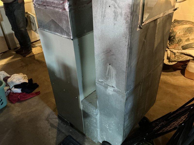 Conducted on-site assessment of existing residential HVAC system for air conditioning replacement estimate. Documented current ductwork configuration in basement utility area, including vertical supply trunk assembly with insulated and bare sheet metal sections, 90-degree elbow joint connections, and overall system layout. Evaluated existing ductwork condition, noting surface wear and accumulated debris on metal components. Photographed mechanical components, structural penetrations, and surrounding utility infrastructure to support replacement system specifications and installation planning.