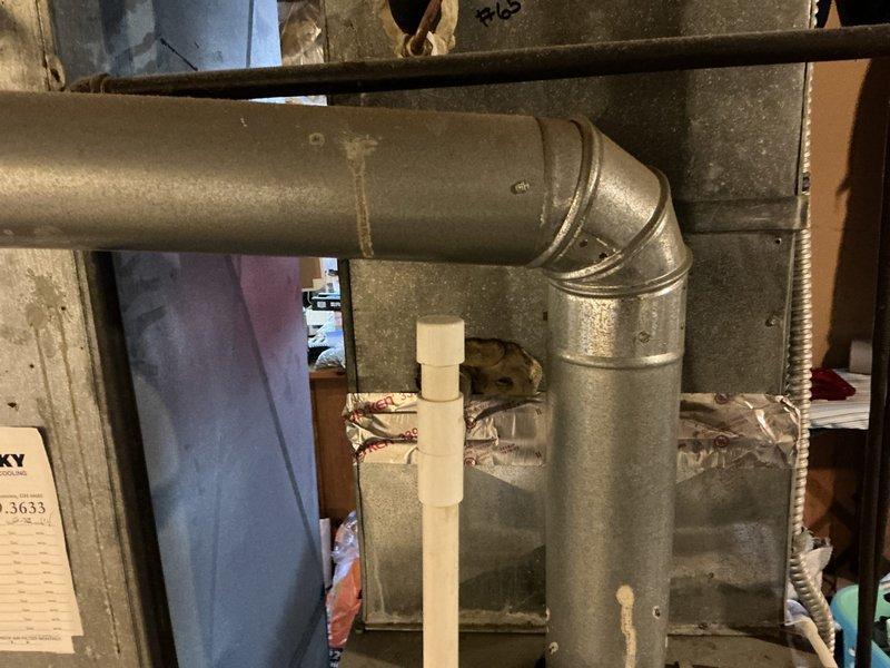 Conducted on-site assessment of existing residential HVAC system for air conditioning replacement estimate. Documented current ductwork configuration in basement utility area, including vertical supply trunk assembly with insulated and bare sheet metal sections, 90-degree elbow joint connections, and overall system layout. Evaluated existing ductwork condition, noting surface wear and accumulated debris on metal components. Photographed mechanical components, structural penetrations, and surrounding utility infrastructure to support replacement system specifications and installation planning.