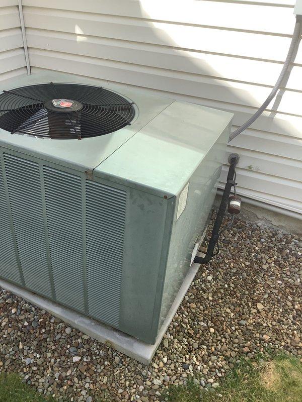 Responded to no cooling complaint on 17-year-old residential air conditioning system. Upon inspection, identified refrigerant leak in outdoor condenser unit. Unit showed significant age-related deterioration with weathered cabinet and components. Provided comprehensive replacement estimate ranging from basic to premium equipment options to address failed system. Documented existing equipment configuration including outdoor condenser unit on concrete pad with gravel base, electrical disconnect box, and refrigerant line routing along exterior wall. Customer quoted for complete system replacement due to age of equipment and extent of refrigerant leak making repair cost-prohibitive.