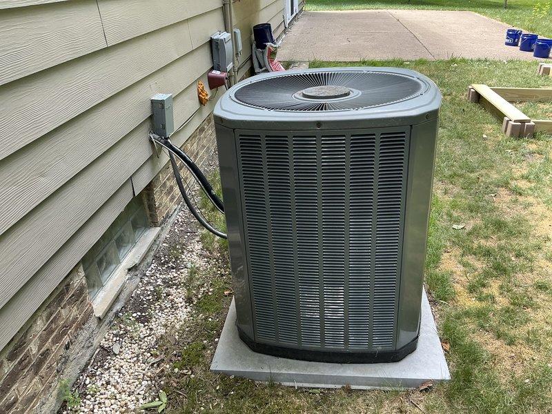 Conducted comprehensive site assessment for HVAC system replacement on residential property with 19-year-old existing equipment. Evaluated current outdoor condensing unit installation, electrical disconnect configuration, and conduit routing along foundation. Documented existing system placement on concrete pad with gravel base, assessed clearance requirements, and photographed electrical connections from wall-mounted disconnect box to unit. Prepared detailed replacement estimate including equipment specifications and installation requirements for aging air conditioning system.