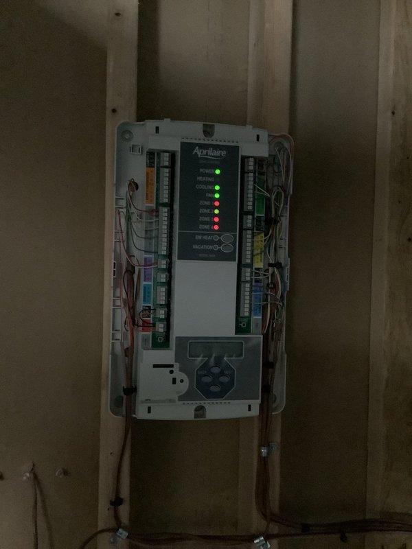 Responded to service call for two-zone HVAC system with communication issues between Ecobee thermostats and Aprilaire zone control panel. Inspected Lennox furnace unit and Aprilaire zone controller, verified wiring connections, and assessed system configuration. Identified improper communication protocol between zone dampers and thermostat controls requiring further programming or equipment compatibility adjustment.