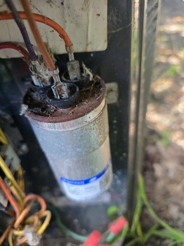 # HVAC Service Completed

Responded to service call for attic air conditioning unit leaking through ceiling with inadequate cooling performance. Unit was running but unable to maintain setpoint temperature, with attic temperature reading 80°F against a 75°F thermostat setting.

Upon inspection, discovered severely corroded dual-run capacitor with extensive rust and oxidation buildup on terminals and wire connections. The deterioration indicated prolonged moisture exposure and component failure, which was causing improper compressor and condenser fan motor operation. This capacitor failure was the primary cause of the cooling deficiency.

Additionally, identified active condensate drainage issue contributing to the ceiling leak. Inspected condensate drain system including primary drain line, secondary overflow line, and drain pan condition.

Replaced failed capacitor with new properly-rated unit, ensuring all electrical connections were secure and properly terminated. Cleared condensate