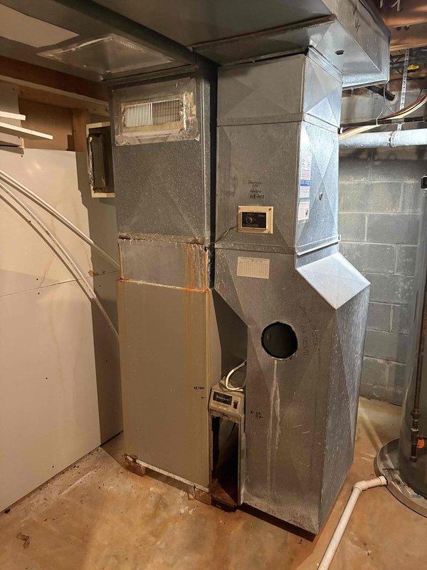 Completed installation of an 80% efficiency furnace and matching air conditioning system. The furnace was elevated and mounted on a platform in the basement mechanical room, with all necessary ductwork connections completed and secured. The outdoor condensing unit was installed on a composite pad in the landscaping bed adjacent to the home's exterior, with refrigerant lines and electrical connections properly routed through the siding to connect with the indoor equipment.
