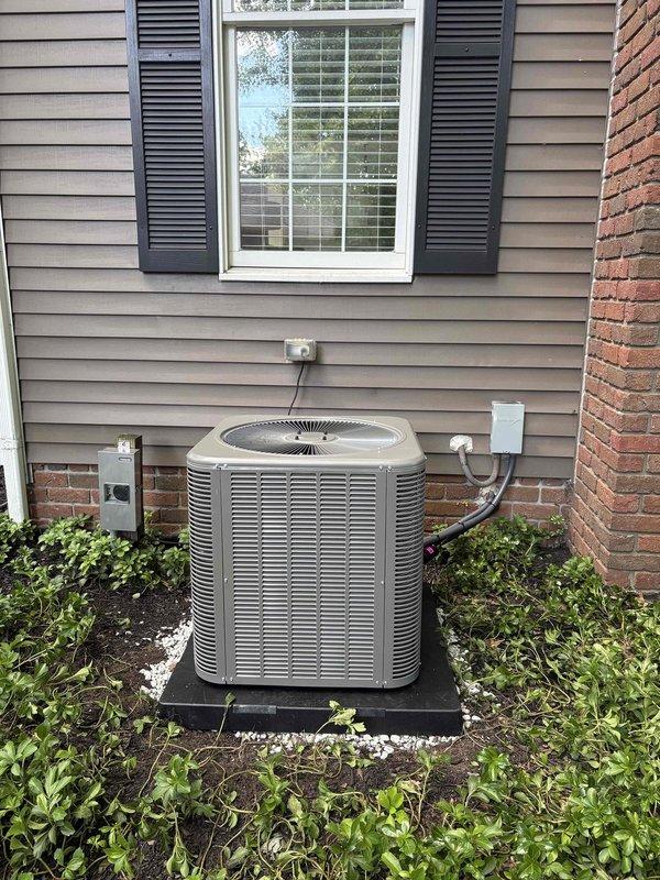 Completed installation of an 80% efficiency furnace and matching air conditioning system. The furnace was elevated and mounted on a platform in the basement mechanical room, with all necessary ductwork connections completed and secured. The outdoor condensing unit was installed on a composite pad in the landscaping bed adjacent to the home's exterior, with refrigerant lines and electrical connections properly routed through the siding to connect with the indoor equipment.