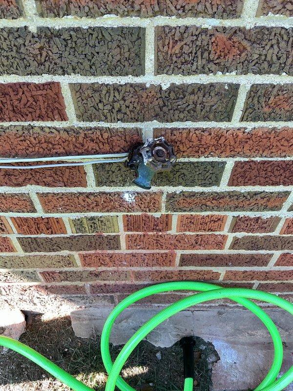 Installed new automatic shutoff valve assembly on main water line in basement of 1960s-era home where no existing valve was previously present. The installation included copper piping with brass fittings mounted to concrete block wall, incorporating a pressure monitoring gauge and white cylindrical reservoir component connected via tubing. Exterior hose bib confirmed operational upon completion of interior valve installation.