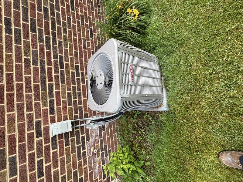 Completed seasonal air conditioning maintenance check on residential cooling system. Performed comprehensive inspection of outdoor condenser unit located on brick paver patio and indoor air handler in basement utility area. Evaluated refrigerant lines, electrical connections, and condensate drainage system with white PVC piping secured to equipment. Inspected ductwork and verified proper mounting of all components. System operational with no immediate service needs identified. Unit age unknown per customer request. Documented equipment condition with photographs for service records.