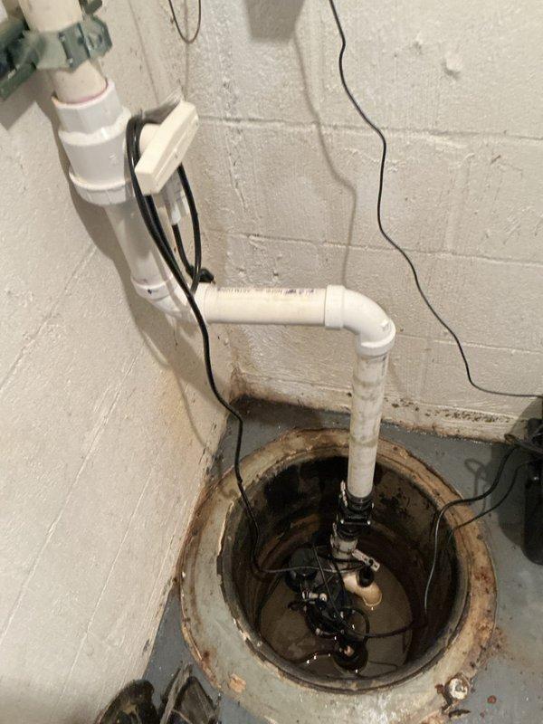 Installed new discharge line for sump pump battery backup system in basement utility area. Work included running white PVC piping with proper fittings and securing to wall with metal clamps, installing new check valve to prevent backflow, and completing all necessary connections to existing sump pump assembly in concrete pit. System tested and operational upon completion.