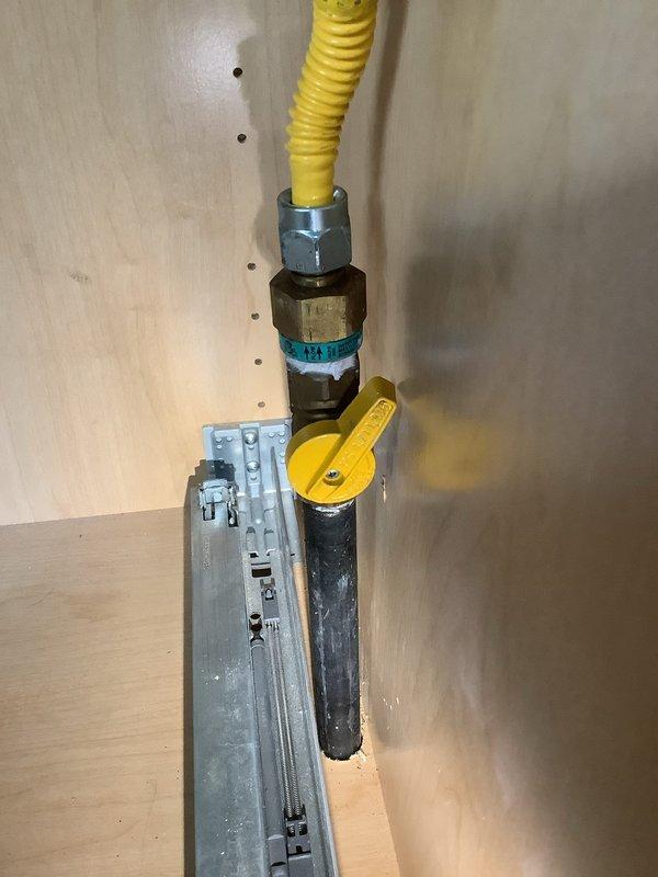 Repaired gas line connection to kitchen gas range by installing new compact ball valve with low-profile yellow handle to meet clearance requirements. Replaced corrugated flexible gas connector and associated fittings, ensuring proper threading and secure connections throughout the assembly. Verified system integrity with leak test and confirmed shutoff valve operates smoothly in confined cabinet space behind cooktop.