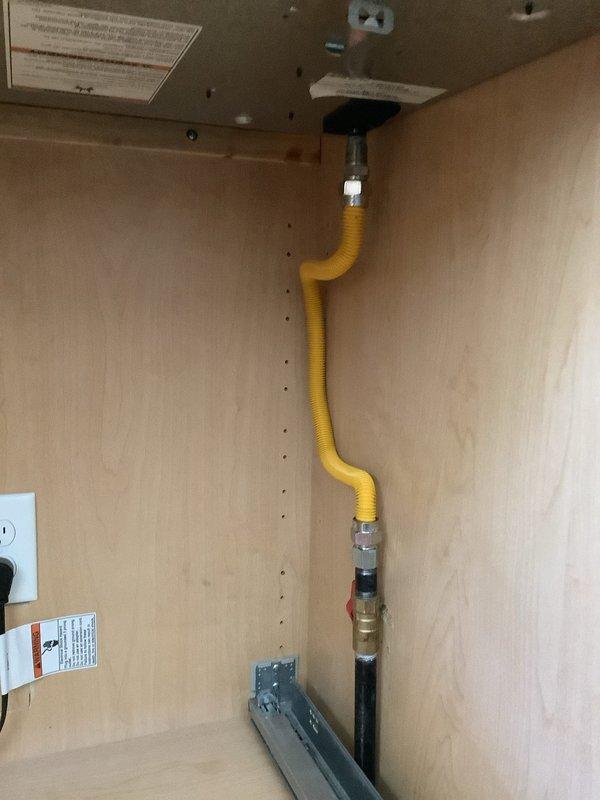 Repaired gas line connection to kitchen gas range by installing new compact ball valve with low-profile yellow handle to meet clearance requirements. Replaced corrugated flexible gas connector and associated fittings, ensuring proper threading and secure connections throughout the assembly. Verified system integrity with leak test and confirmed shutoff valve operates smoothly in confined cabinet space behind cooktop.