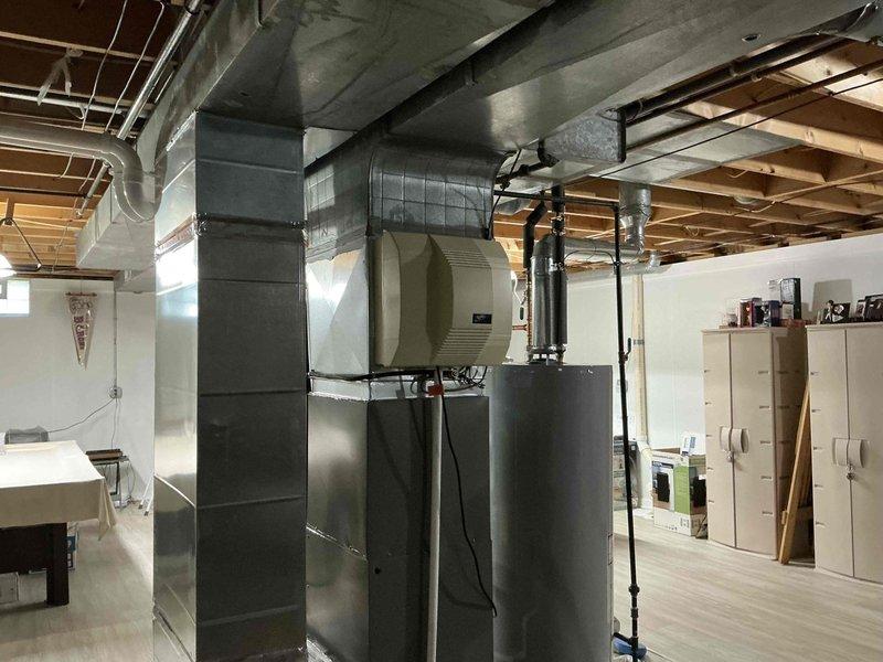 Provided estimate for whole-home dehumidifier installation to existing HVAC system in basement utility area. Assessed current ductwork configuration and identified optimal integration point for dehumidifier unit with main air handler. Documented existing system layout including rectangular metal ductwork, exposed joists, and available clearances for equipment placement. Took measurements and photographs to determine proper sizing and installation requirements for IAQ equipment upgrade.