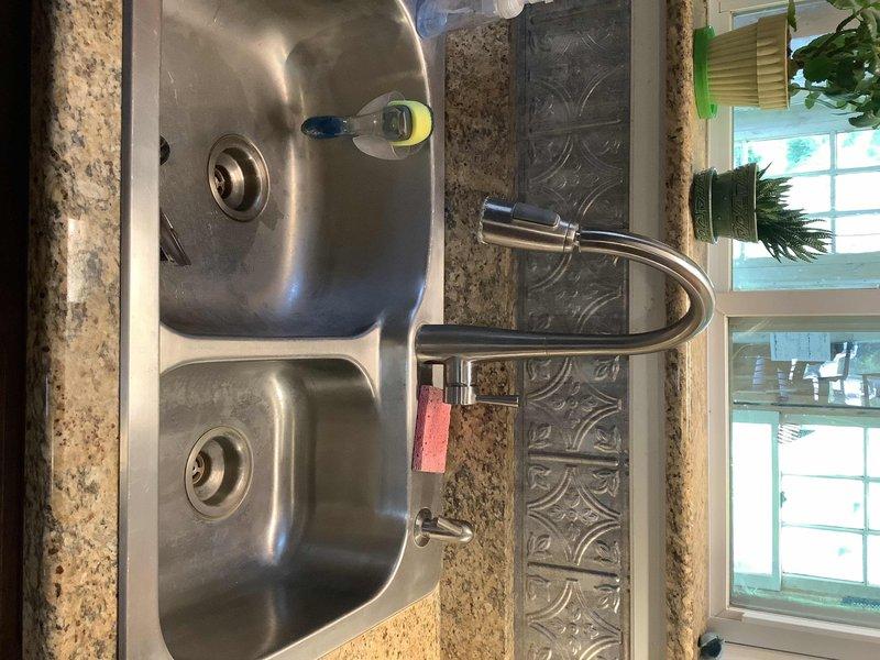 Responded to service call for leaking kitchen sink. Upon inspection, identified water leak originating from under-sink plumbing assembly in basement area beneath fixture. Repaired compromised connections in PVC drain line system and verified integrity of supply line fittings at copper-to-brass connections. Tested all plumbing connections under pressure, confirmed leak resolution, and verified proper drainage from double-basin stainless steel sink with pull-out faucet fixture.