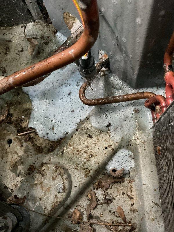Responded to service call for air conditioning unit not cooling properly. Upon inspection, found heavily clogged condensate drain pan with significant mineral buildup, sediment accumulation, and corrosion on copper drain lines. Cleaned drain pan, flushed drain lines, and verified proper condensate drainage to restore system functionality and cooling performance.