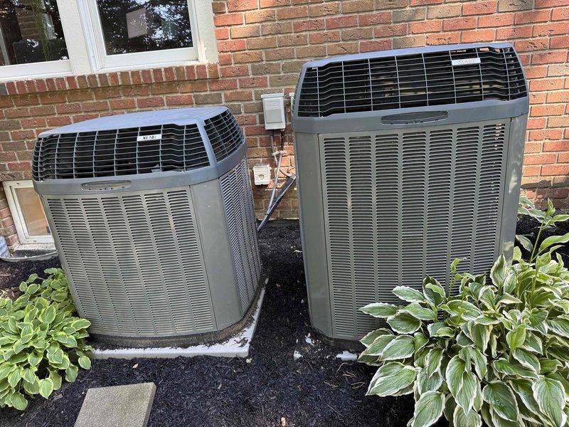 Responded to no cooling call on 10-year-old residential system. Customer has two HVAC units on property. Upon inspection, found evaporator coil exhibiting significant white and yellowish-white buildup and discoloration across fin surfaces, particularly concentrated in upper and middle sections. This contamination was restricting airflow and reducing heat transfer efficiency, resulting in inadequate cooling performance. Both outdoor condenser units located at exterior brick wall appeared in good working condition with clean exteriors and intact components. Documented coil condition with photos showing extensive deposit accumulation on aluminum fins and darkened copper refrigerant lines indicating age and oxidation. System requires coil cleaning or replacement to restore proper cooling operation.