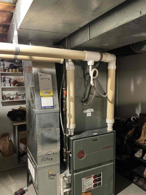 Conducted on-site evaluation for complete HVAC system replacement of 28-30 year old furnace and air conditioning equipment. Assessed existing basement-mounted gas furnace with attached air handler and outdoor condensing unit, both operating but at end of serviceable life. Documented current system configuration, ductwork connections, electrical service, and equipment placement for replacement specifications. Photographed indoor and outdoor units to determine proper sizing requirements and installation considerations for new equipment.