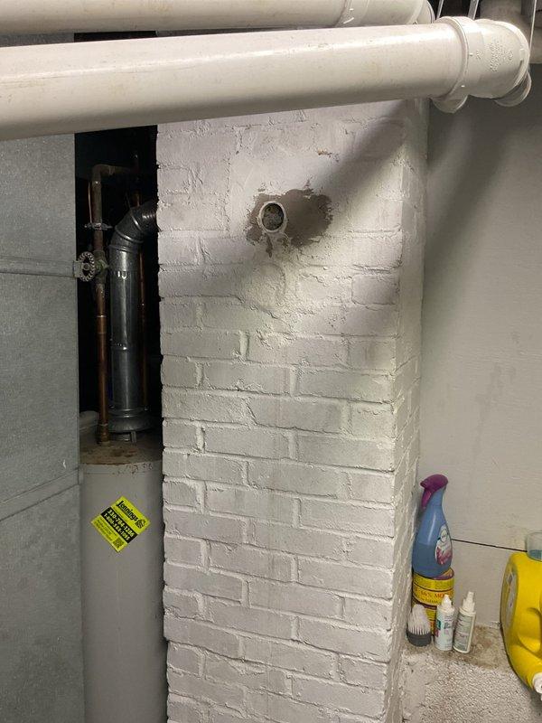 Applied high-temperature furnace cement to seal a compromised penetration in the basement utility area where discoloration and paint deterioration indicated heat exposure around a circular opening in the painted brick wall. Supplies were procured and delivered to complete the permanent repair, restoring the integrity of the wall penetration and preventing further heat damage to the surrounding painted surface.