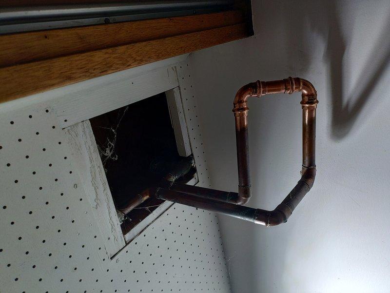Removed existing water treatment system and reconfigured overhead water lines by plumbing them together with copper piping to restore proper water flow. Performed complete flush and fill service on the water heater to remove sediment buildup and replaced the thermal expansion tank to ensure proper system pressure regulation. All work completed using truck stock materials with new copper pipe routing visible in utility area.