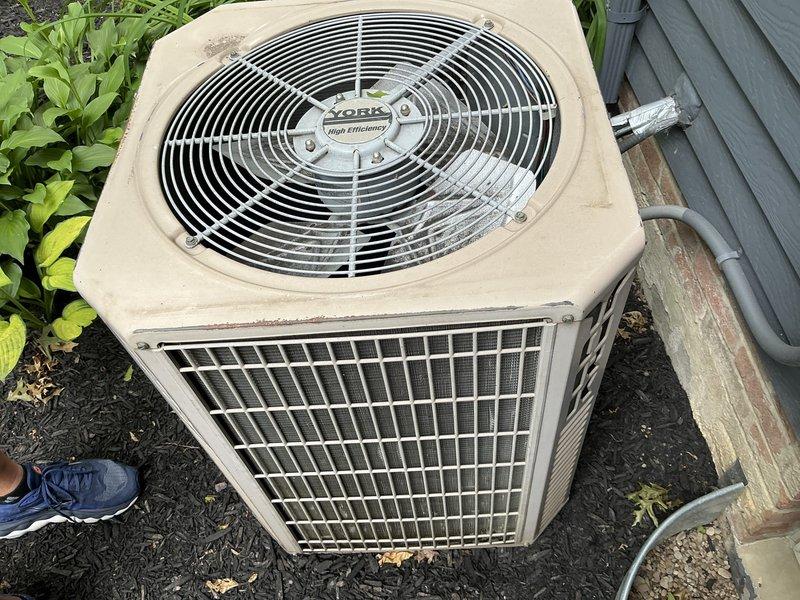 Provided estimate for complete HVAC system replacement in medium-sized residential property. Assessed existing York high-efficiency outdoor condensing unit showing weathering and outdoor exposure, along with basement ductwork configuration featuring galvanized steel supply runs with curved elbow transitions and support brackets. Quoted Lennox vertical upflow/downflow gas furnace and air conditioning system suitable for 1500-3000 square foot heating and cooling application with natural gas or propane fuel source and basement installation location.