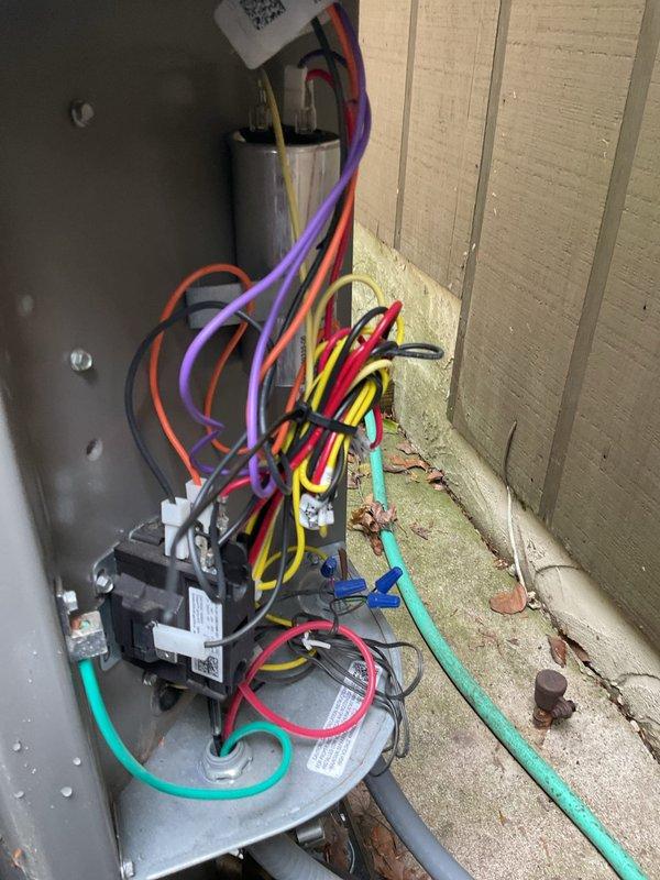 Responded to service call for air conditioning condenser unit experiencing excessive noise levels approximately 11 months after installation. Upon arrival, confirmed system was maintaining proper cooling capacity despite increased operational sound. Performed thorough inspection of condenser unit including examination of fan assembly, motor mounts, and electrical components. Inspected control panel containing capacitor and contactor with associated wiring connections. Evaluated fan grille, blades, and motor operation for potential sources of noise including loose components, bearing wear, or mounting issues. Documented equipment condition through photographic records showing electrical panel configuration and condenser fan assembly. System continues to operate and cool effectively.