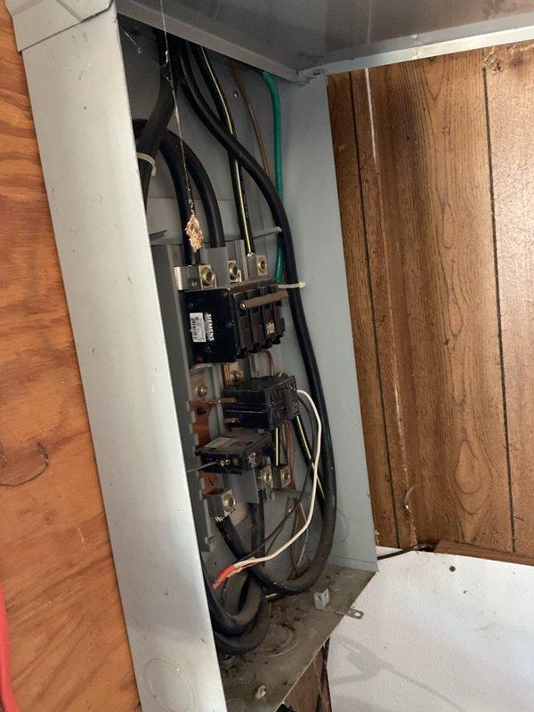 Installed new electrical service panel in wall cavity with main disconnect breaker and multiple circuit protection devices. Completed all wire terminations using proper color-coded conductors (black, green, white) to brass terminal blocks and breakers, with meter socket connection configured for AC circuit operation. Panel mounted securely in gray metal enclosure with all connections tested and verified for safe operation.