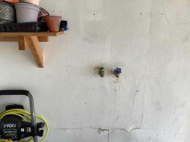 Responded to service call for leaking exterior hose bib that was recently installed. Upon inspection, identified leak at brass spigot connection point on exterior wall. Tightened compression fittings, verified proper sealing of threads, and tested water flow at both the brass hose bib with green handle and adjacent blue-handled valve to ensure no further leakage. System tested and confirmed operational with no active leaks detected.