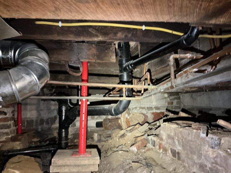 Responded to main drain backup issue at residential property. Upon inspection of crawl space and basement areas, assessed drainage system including visible PVC/ABS piping network and identified source of backup. Documented extensive moisture damage and standing water on basement floor, along with deteriorated foundation conditions showing long-term water exposure and efflorescence on masonry walls. Evaluated structural support systems and utility routing in crawl space to access affected drain lines. Cleared main drain obstruction and restored proper flow to system. Verified all fixtures draining correctly upon completion.