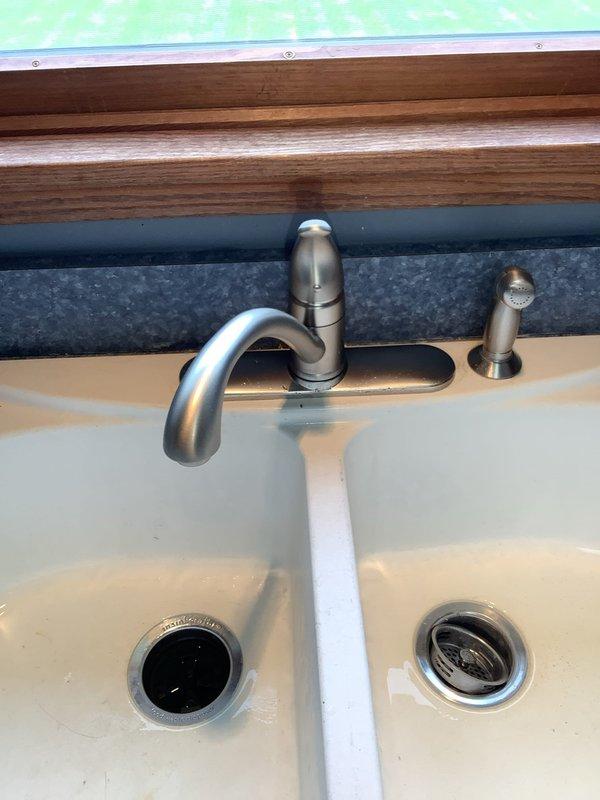 Replaced kitchen faucet at residential property due to wear and functionality issues. Removed existing brushed stainless steel faucet assembly including spray attachment, disconnected supply lines from underneath sink, and installed new faucet with matching finish. Inspected supply line connections during installation and noted significant copper corrosion and mineral buildup on water supply pipes beneath the sink, typical of aging plumbing systems. Tested new faucet for proper operation and verified no leaks at connection points.