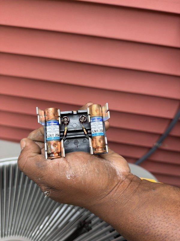 Completed installation of replacement air conditioning unit and coil system located beneath rear deck of Building 1. Unit positioned in screened area behind property, shielded by existing tree line for aesthetic purposes. Verified and replaced FLNR 25A electrical fuses as part of electrical disconnect service, ensuring proper amperage protection for new system startup and operation.