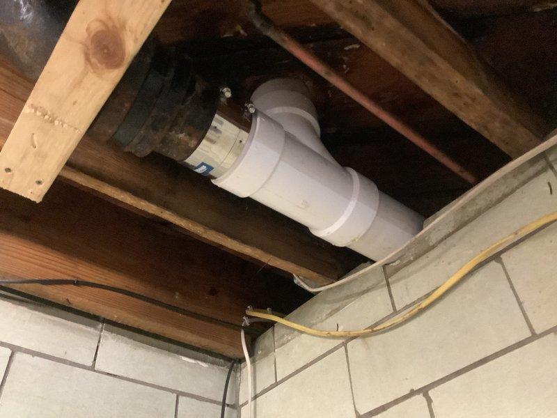 Responded to warranty callback for persistent toilet leak. Upon inspection, confirmed previous repair was unsuccessful due to improper toilet flange height causing seal failure. Assessed PVC drainage system configuration in basement area, including vertical stack and horizontal connections. Identified flange installation issue requiring correction to achieve proper toilet mounting and watertight seal. Documented plumbing infrastructure including drainage lines, fittings, and connections for repair planning.