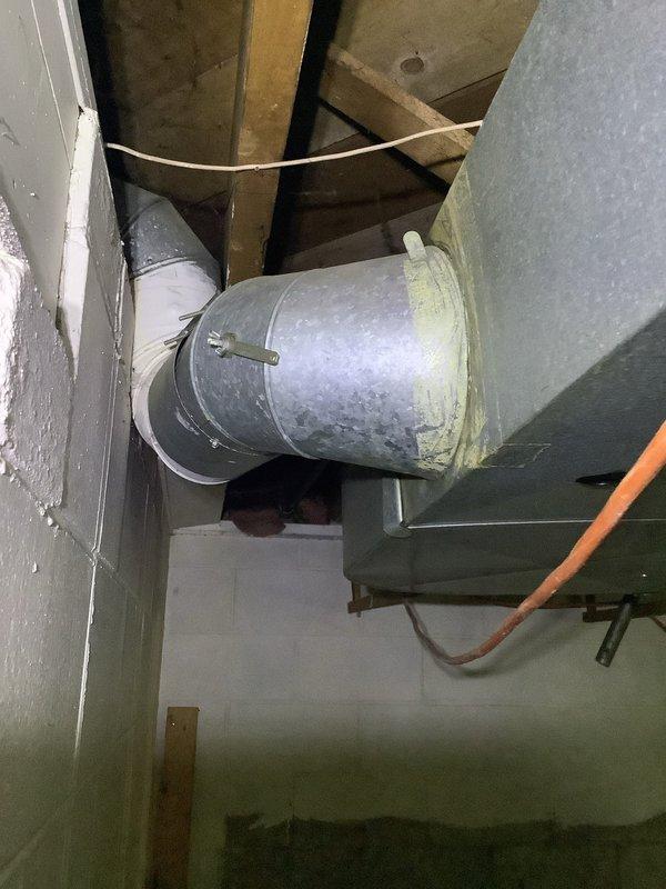 Responded to service call for detached ductwork elbow in basement utility area. Upon inspection, found large cylindrical metal supply duct with disconnected elbow joint. Reattached and secured elbow connection to main duct run, restoring proper airflow through the HVAC system and eliminating potential conditioned air loss into the unconditioned space.