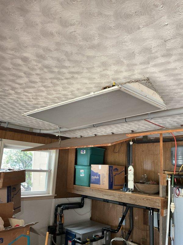 Completed electrical estimate for fixture assessment in garage/workshop space. Evaluated existing ceiling-mounted light fixture requiring repositioning or replacement, and assessed decorative chandelier-style fixture with multiple arms and frosted glass shades in adjacent workspace area. Documented current electrical fixture conditions and provided recommendations for repair or upgrade options.