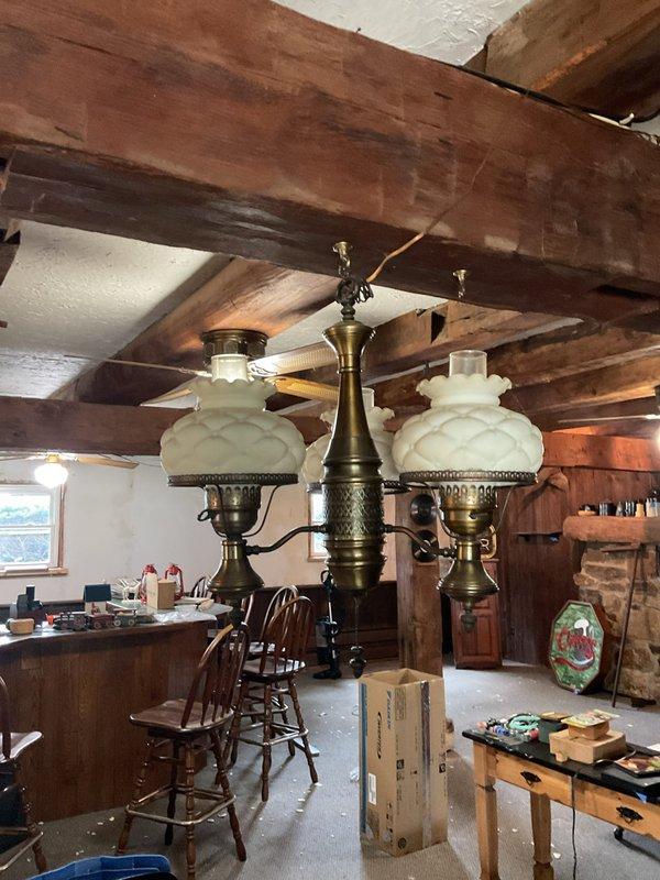 Completed electrical estimate for fixture assessment in garage/workshop space. Evaluated existing ceiling-mounted light fixture requiring repositioning or replacement, and assessed decorative chandelier-style fixture with multiple arms and frosted glass shades in adjacent workspace area. Documented current electrical fixture conditions and provided recommendations for repair or upgrade options.