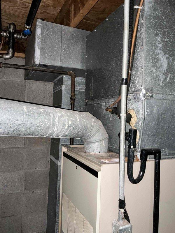 Conducted on-site assessment of existing HVAC system in basement mechanical room to provide replacement estimate for furnace and air conditioning equipment. Evaluated current air handler unit, ductwork configuration, and associated piping systems including copper refrigerant lines and PVC condensate drainage. Documented existing installation conditions, noting dust accumulation on flexible ductwork and aging infrastructure. Photographed equipment specifications, clearances, and utility connections to determine proper sizing and compatibility requirements for replacement system.