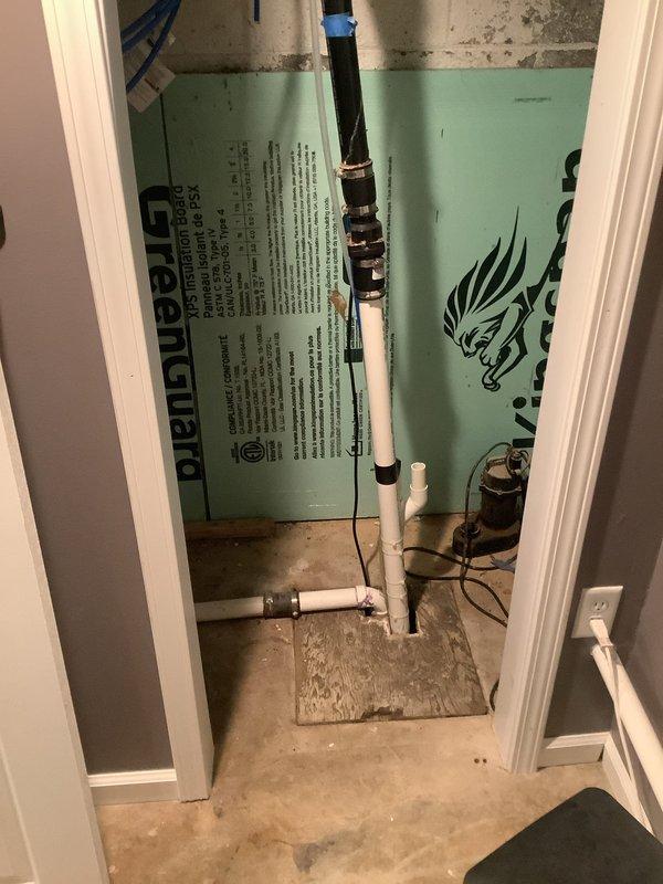 Completed rerouting of sump pump discharge line and shower drain in unfinished basement utility area. Installed new white PVC drainage piping with proper fittings and connections through exposed framing and concrete block walls, ensuring proper pitch and code-compliant installation for effective water removal.